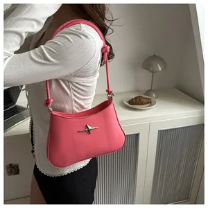 Detail of a pink leather shoulder bag featuring a silver star ornament and knotted strap