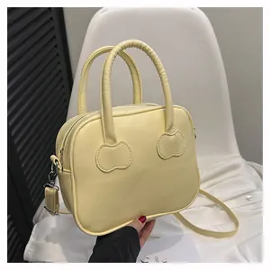 Detail of cream yellow leather handbag with unique curved stitching and silver metal hardware