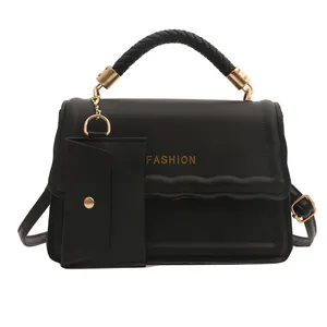 Sac à main noir avec poignée tressée, détails dorés et mini pochette sur fond blanc pur