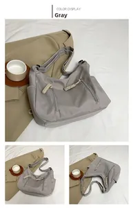 Detail view of grey nylon tote bag with double zipper pockets and woven pullers