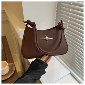 Close-up of dark brown leather crescent bag with star rivet and knotted strap detail