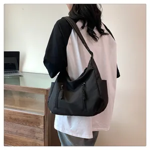Detail of black nylon tote bag with multiple pockets and woven zipper pulls worn by a model