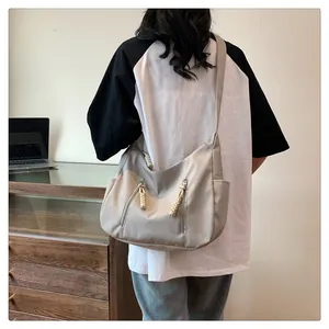 Detail view of large nylon tote bag featuring multi-pocket design and woven zipper pulls