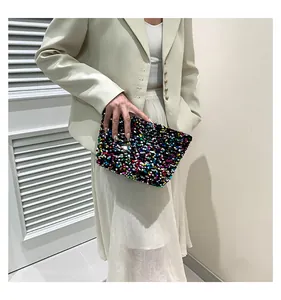 Macro view of vibrant sequins texture on the fashion clutch bag held by a model