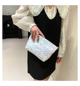 Close-up of white iridescent sequin clutch with gold zipper and pearlescent shine