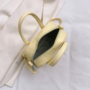 Minimalist light yellow PU leather handbag with adjustable strap on white fabric background