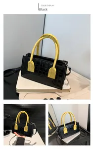 Dettaglio borsa nera con trama a coccodrillo, manico giallo e cuciture incrociate alla moda