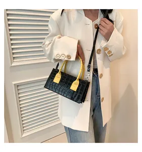 Borsa a mano alla moda con cuciture a contrasto e motivo a pietra su un abito bianco