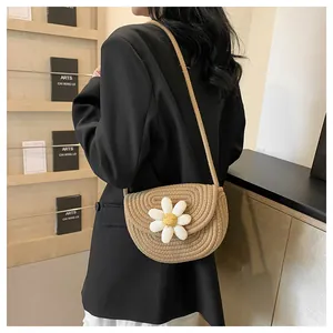 Detail view of a beige woven flower crossbody bag worn by a model in a black blazer