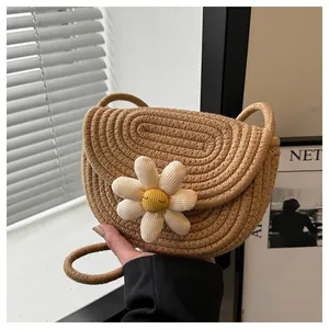Close-up of woven straw shoulder bag featuring a white 3D daisy with an embroidered face