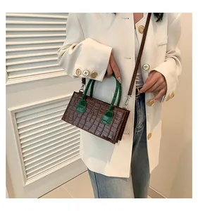 Dettaglio della trama a coccodrillo su borsa in pelle marrone scuro con manico verde