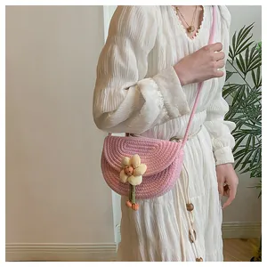 Detailed shot of pink crochet saddle bag with 3D yellow flower on white pleated dress