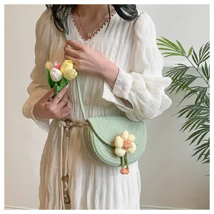 Detail of mint green woven saddle bag with large floral applique and spiral knit texture