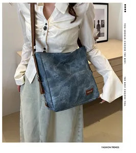 Close-up of vintage blue denim tote with brown leather label and adjustable shoulder strap