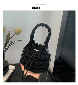 Detail of black cloud bucket bag with bubble texture, chain strap, and drawstring closure