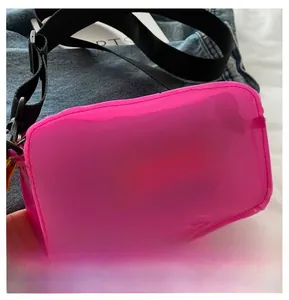 Detail of pink transparent PVC mini bag with white text and adjustable black nylon strap