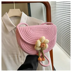 Detail of pink woven shoulder bag featuring a yellow fabric flower and artisan cotton texture