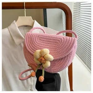 Close-up of pink woven cotton shoulder bag featuring a yellow floral detail and orange charms