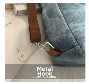 Close-up of durable silver metal hook and brown fabric strap on denim handbag