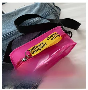 Detailed close-up of pink transparent PVC crossbody bag with yellow lettered zipper strap