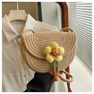 Close-up of handmade woven saddle bag with 3D floral accent on creamy cotton rope texture
