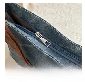 Detail of smooth metal zipper and blue denim fabric on this large capacity tote bag