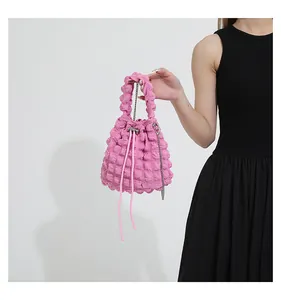 Detail of pink popcorn textured drawstring bucket bag with chain strap on a model