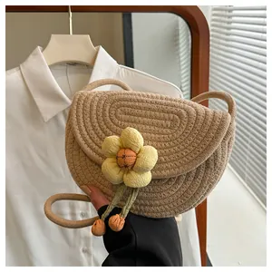 Detail of a beige woven shoulder bag with a large 3D yellow flower and leaf tassels