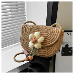 Detail of hand-woven crossbody bag with large floral accent and green stem decorations