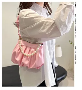 Pink ruched cloud bag with pearl chain detail worn as a stylish underarm shoulder bag