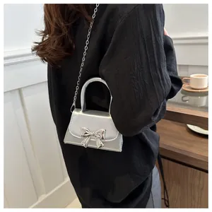 Silver metallic mini crossbody bag featuring a bow buckle and delicate chain strap