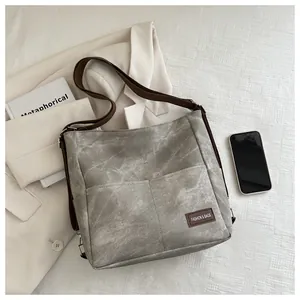 Detail view of washed gray denim tote bag with functional pockets and stylish brand label
