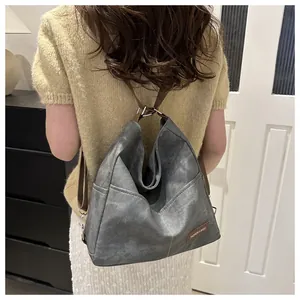Detail showing the gray retro backpack with brown straps and brand label in home setting