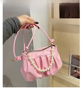 Detailed shot of pink ruched shoulder bag with pearl chain and knotted handle design