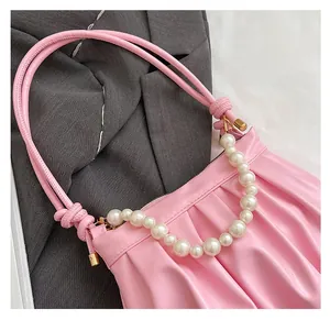 Detail of pink ruched shoulder bag featuring large pearl chain and soft textured pleats