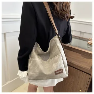 Detail of grey washed canvas hobo bag with adjustable brown strap and leather label