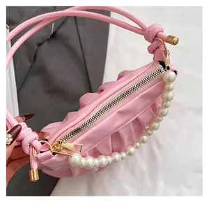 Detail of smooth gold zipper and white faux pearl handle on pink pleated leather bag