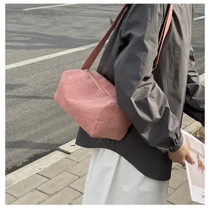 Detailed close-up of pink corduroy texture and wide strap on this stylish crossbody bag