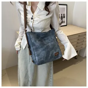 Close-up of denim shoulder bag with brown adjustable strap and Fashion & Bags brand tag
