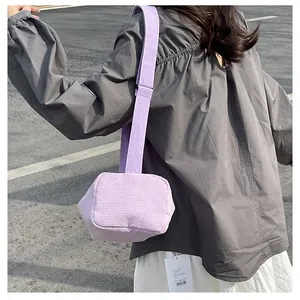 Detail view of the lavender corduroy shoulder bag with wide strap on a model