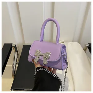 Close-up of lilac mini handbag with large metallic silver bow and chain strap detail