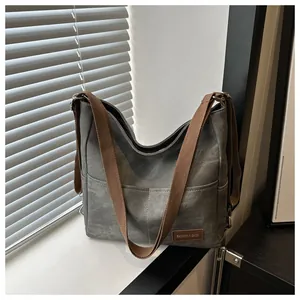 Detail of grey-green canvas hobo bag showing outer pockets and brown fashion leather tag