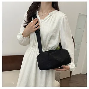 Detail view of black corduroy cylinder crossbody bag with wide nylon shoulder strap