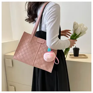 Detail of pink woven tote bag featuring a peach plush charm and fashion leather tag