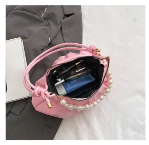 Pink pleated cloud bag with pearl chain detail showing spacious interior for cosmetics