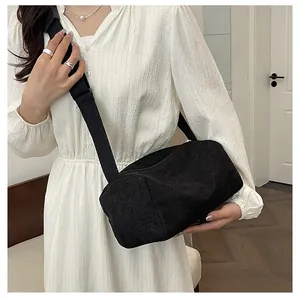 Detail of black corduroy cylinder crossbody bag showing fabric texture and wide strap