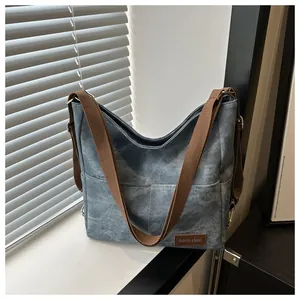 Close-up of vintage washed denim blue canvas bag with brown strap and leather patch detail