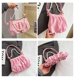 Detail of pink ruched cloud bag featuring elegant pearl handle and soft leather texture