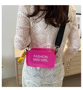 Detail of transparent rose pink jelly bag with black fabric strap and yellow decorative tag