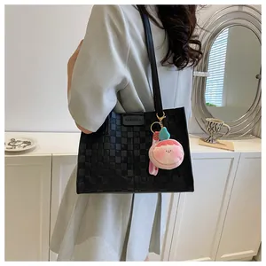 Detail of black woven large tote bag with pink peach charm on a gray blazer suit